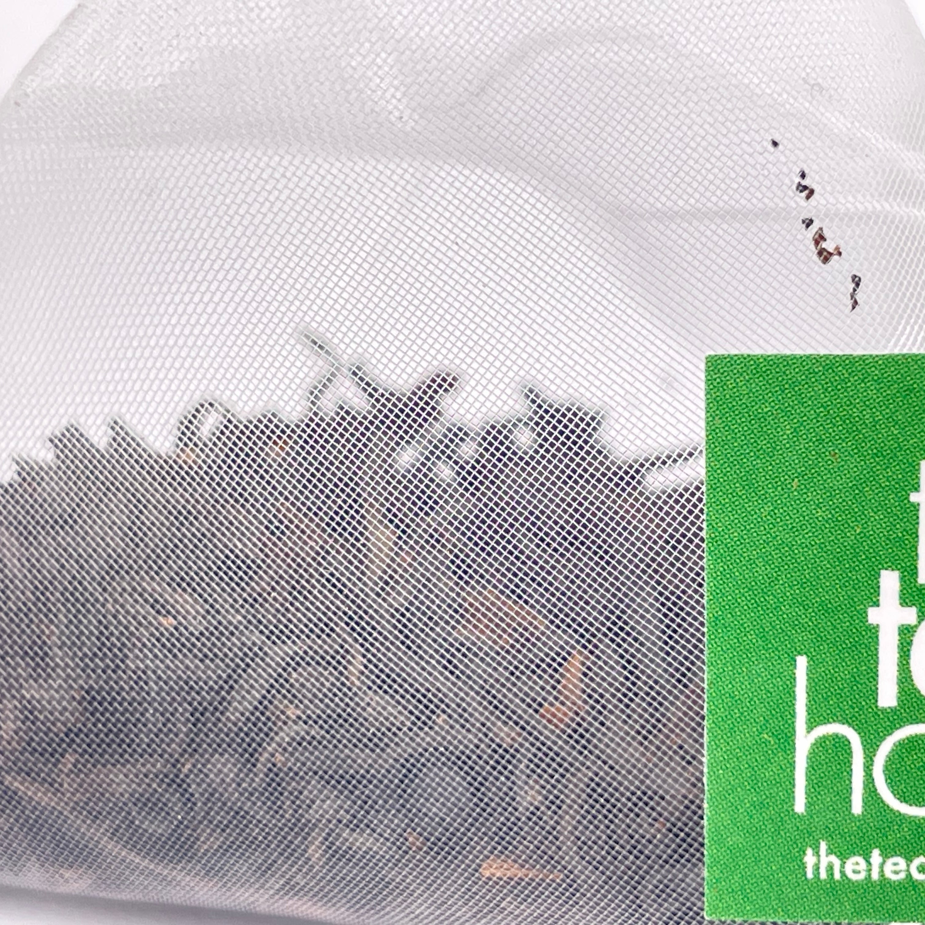 teabag containing loose leaf tea with green and white tag