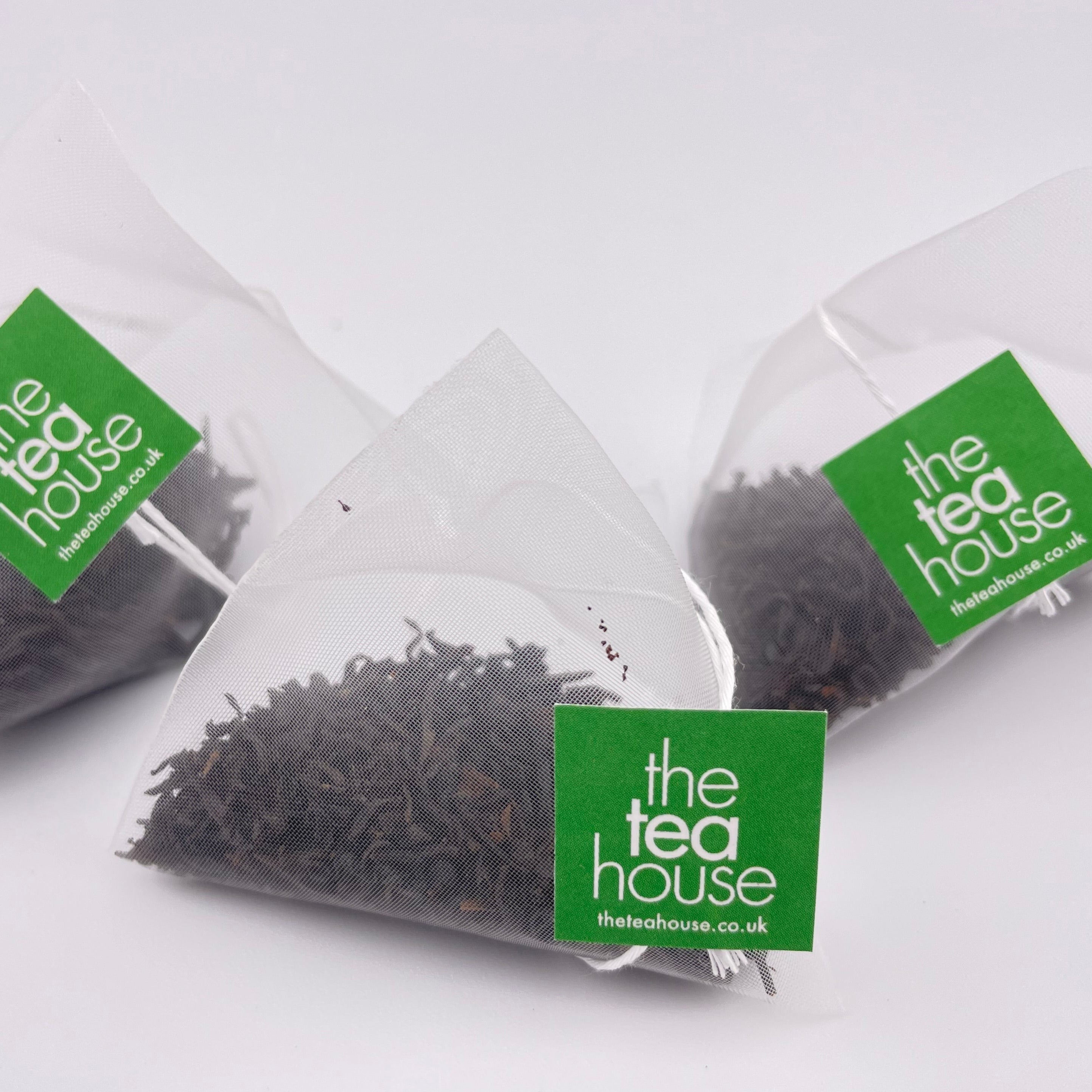 Teabags containing loose leaf tea on white background