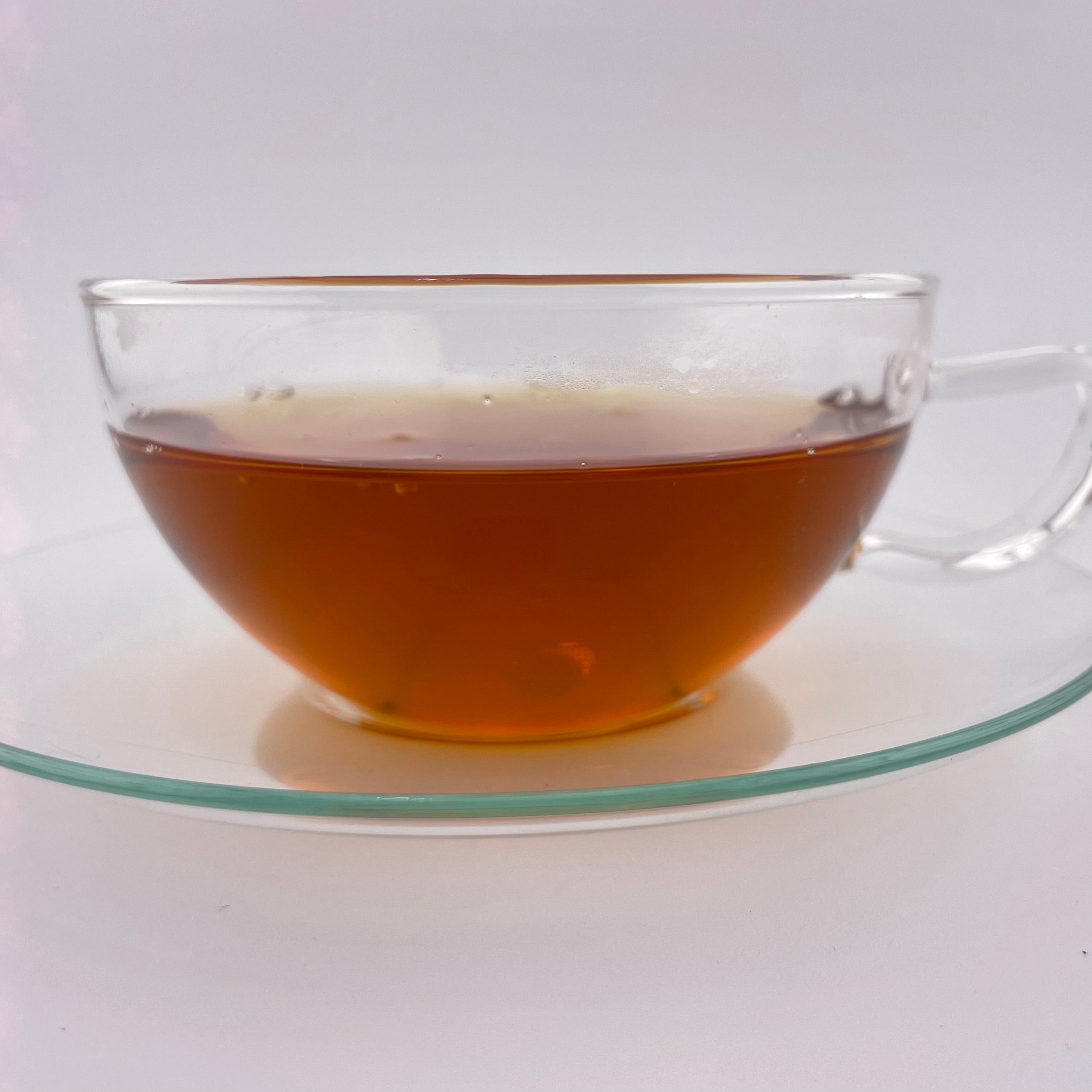 Clear glass teacup with tea on a white background