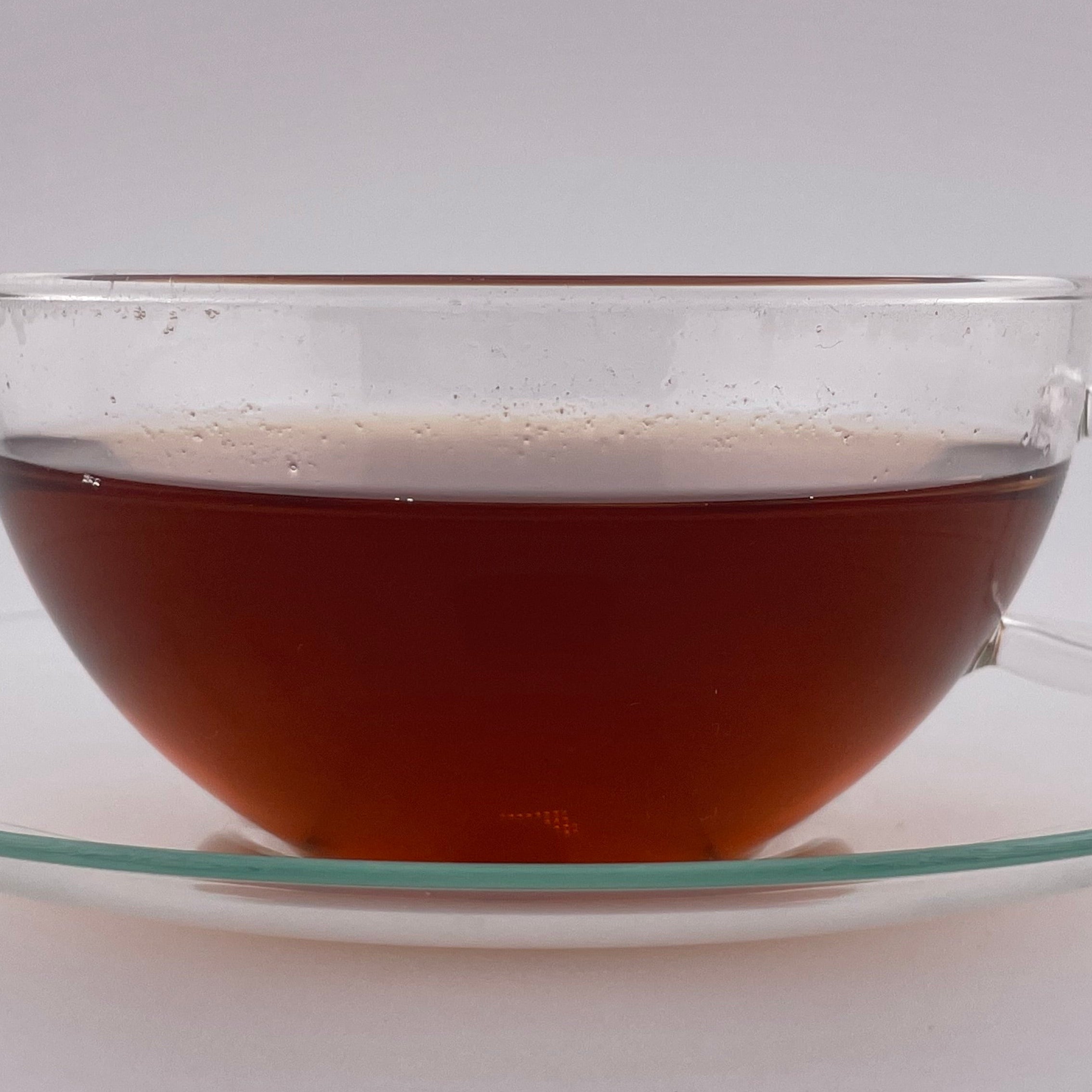 Clear glass teacup with tea on a white background