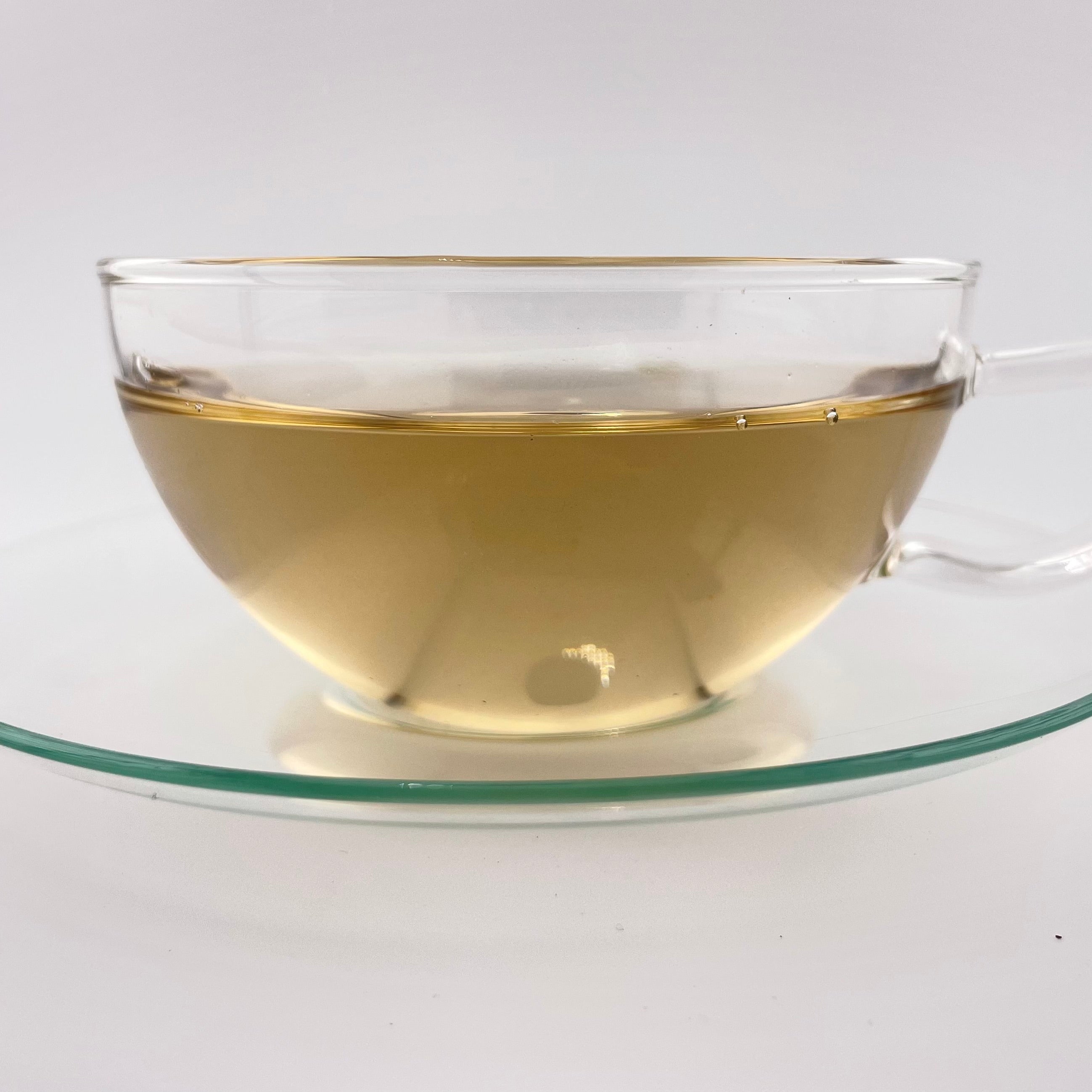 Clear glass teacup with tea on a white background
