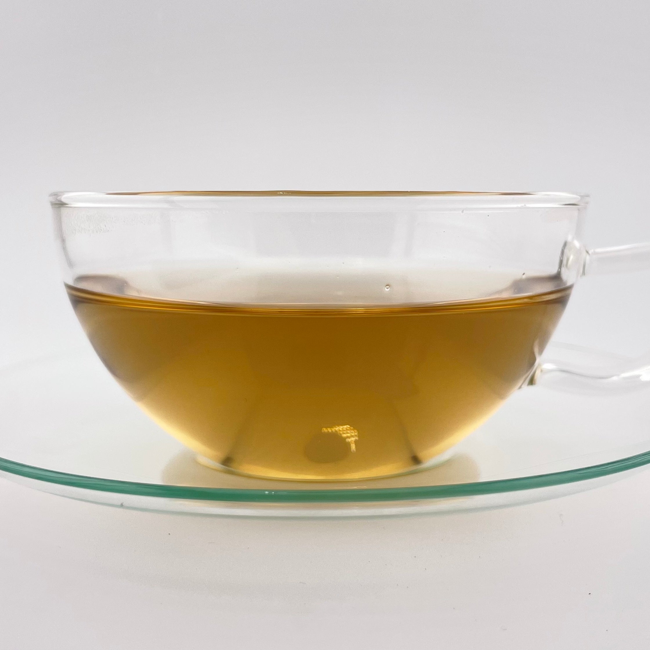 Clear glass teacup with tea on a white background