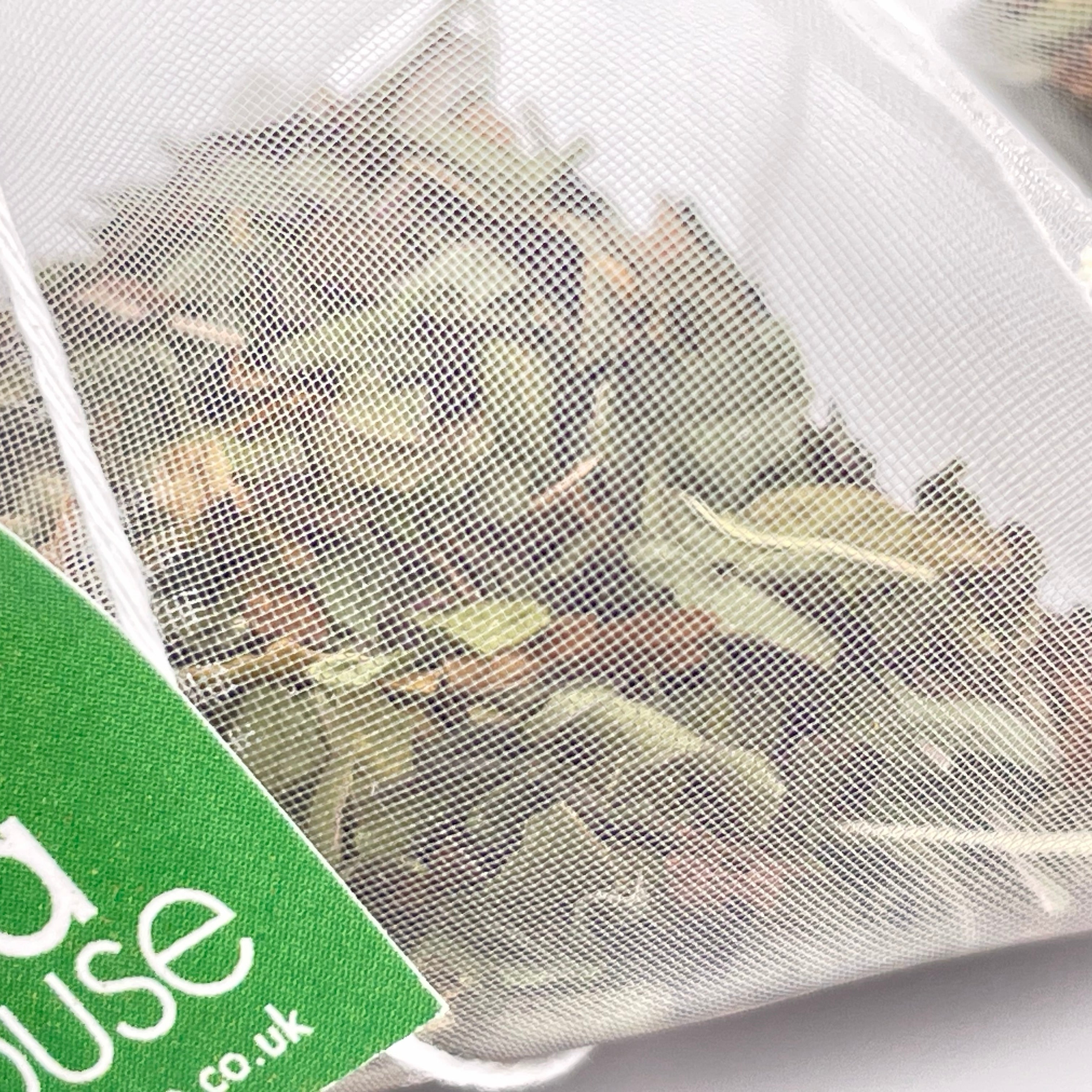 loose leaf peppermint in a teabag on white background with green tag "The Tea House"