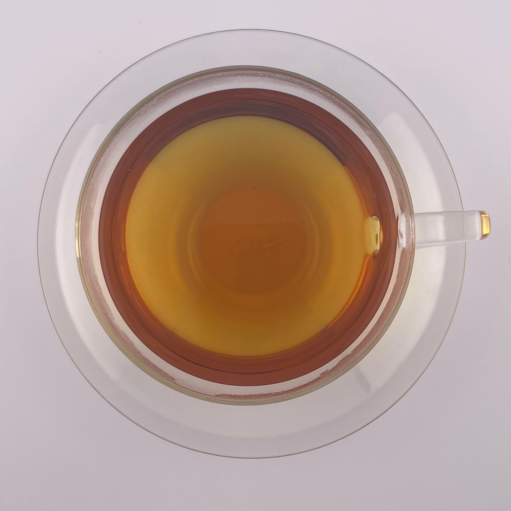 Clear tea cup with a yellowish liquid on a white background