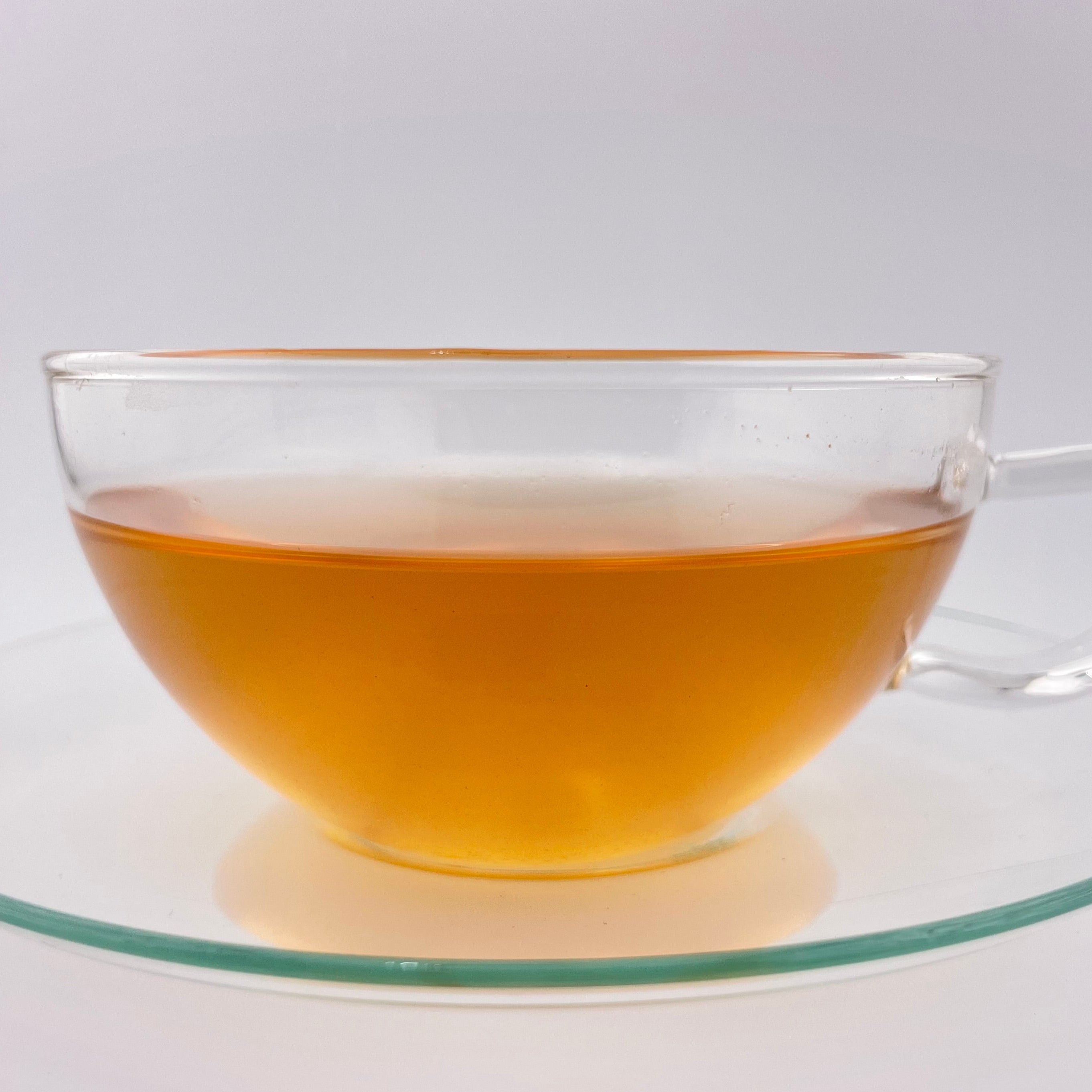 yellow orange liquor in clear teacup on white background