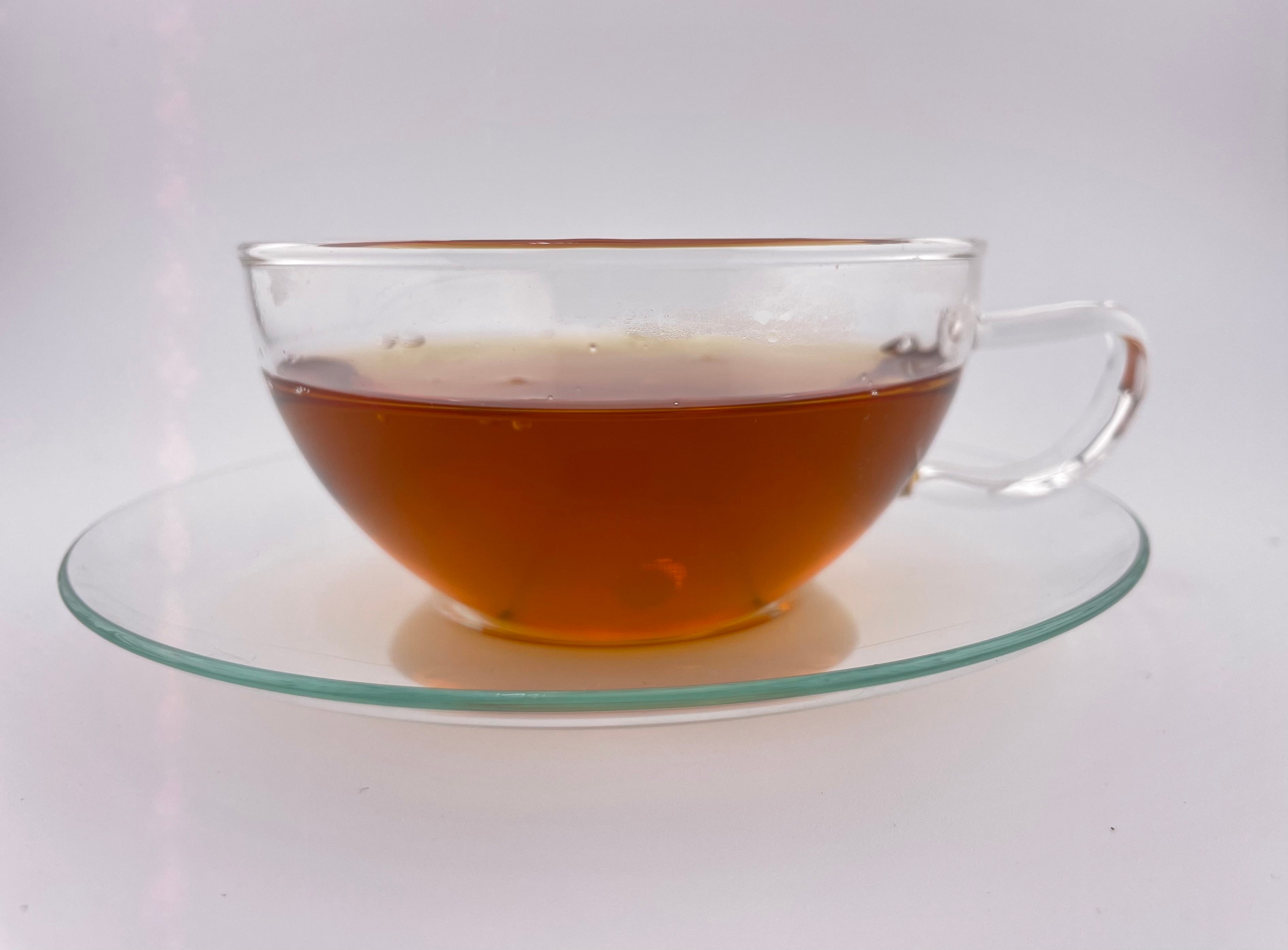 Clear glass teacup with tea on a white background