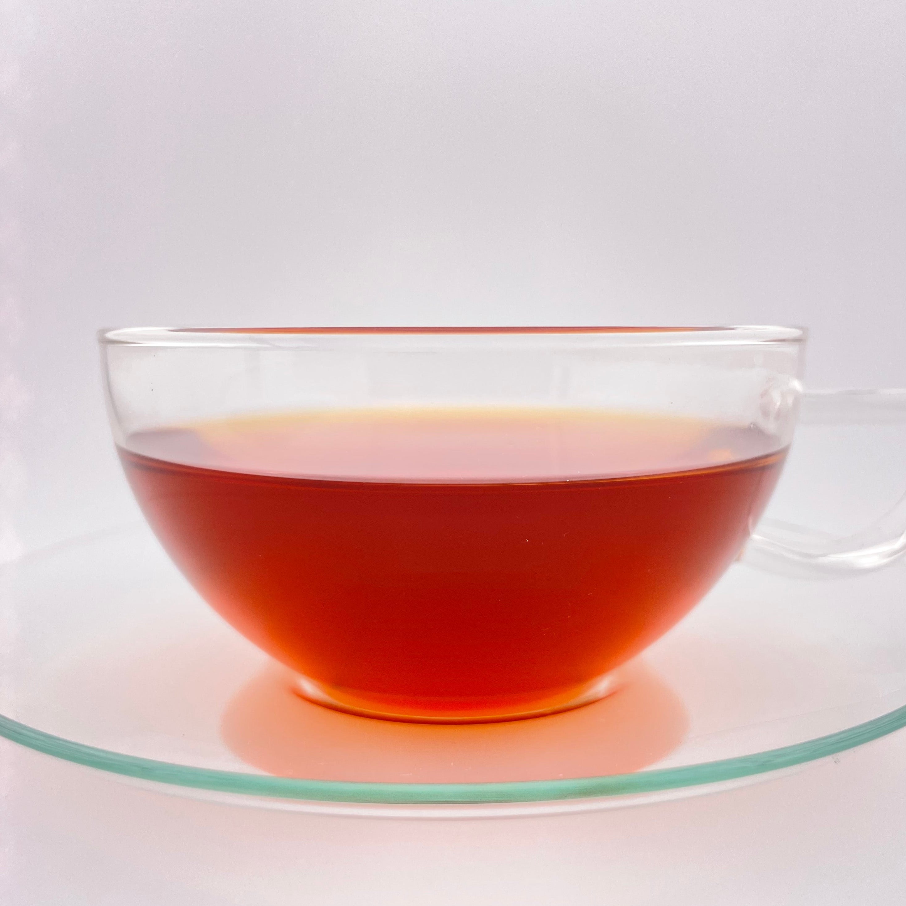 Clear glass teacup with red tea on a white background