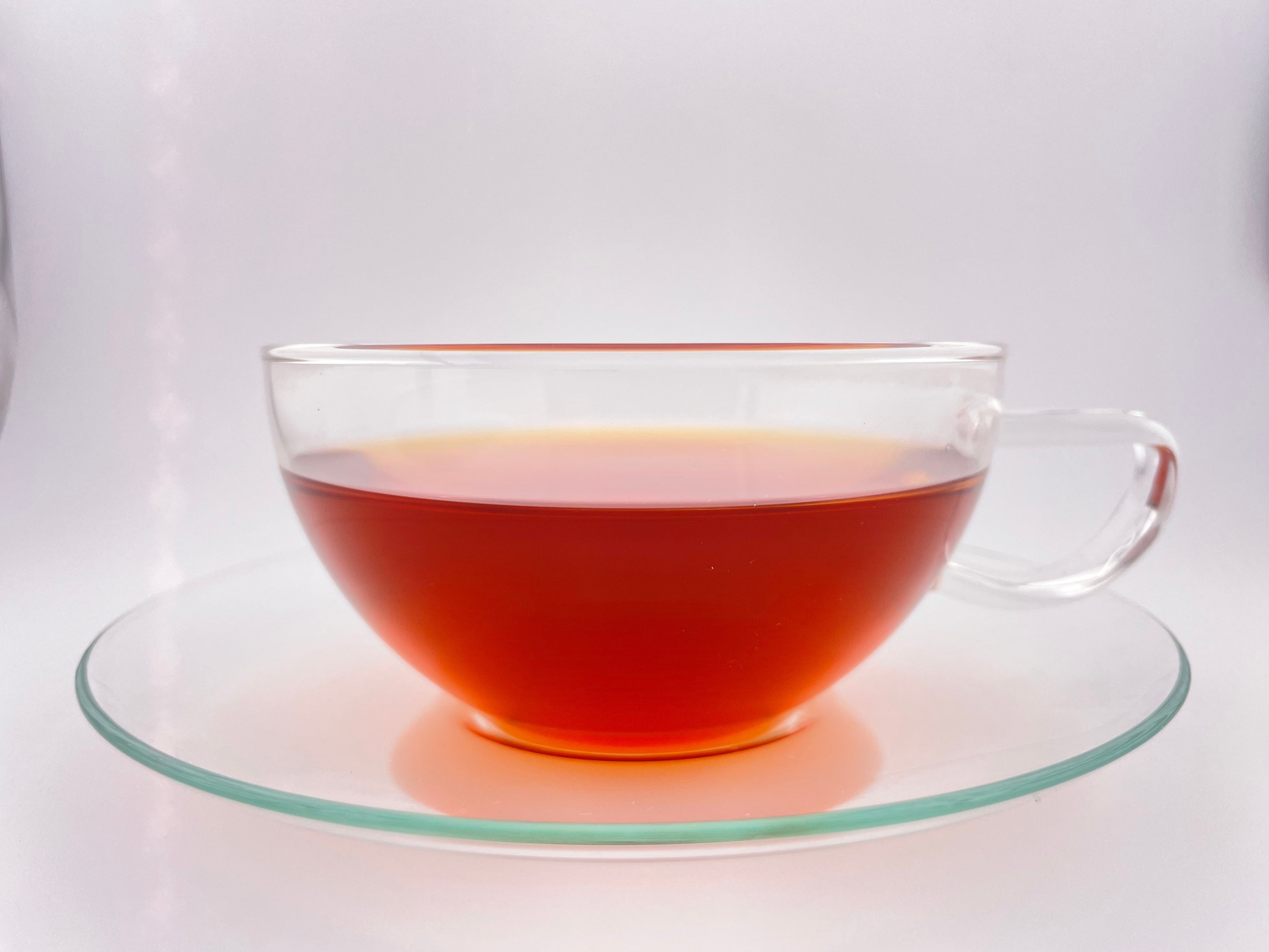 Clear glass teacup with red tea on a white background