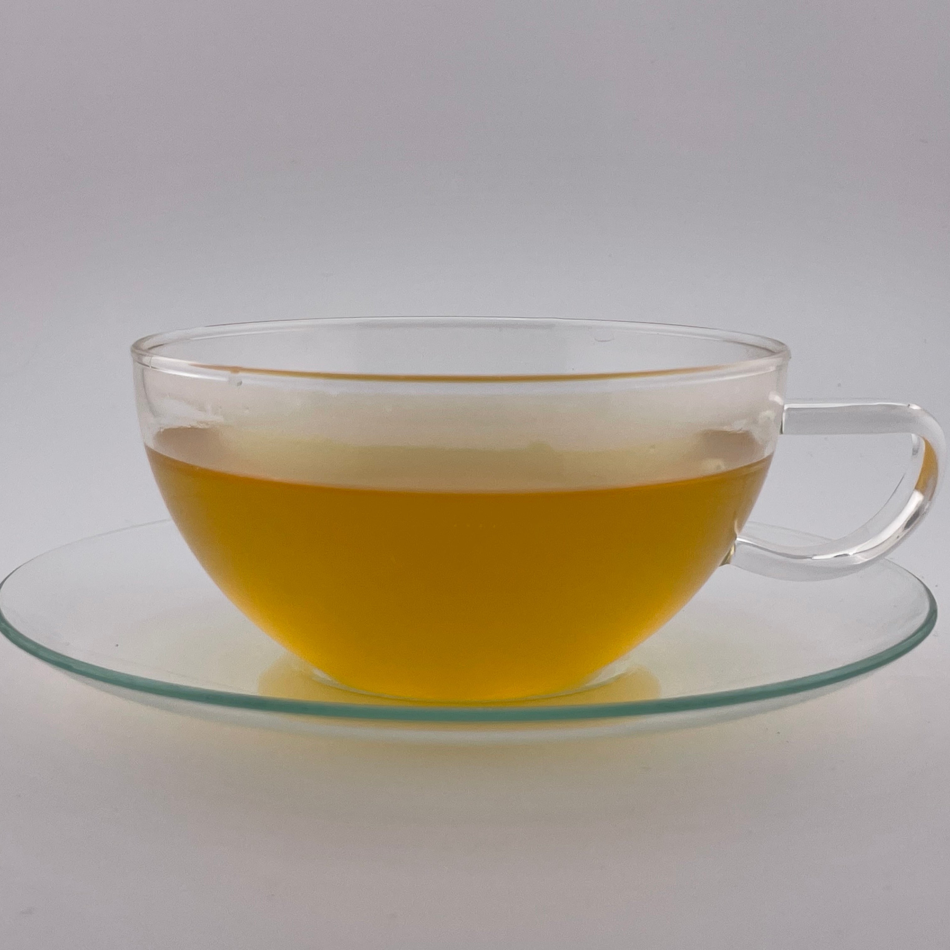 yellow liquor in a clear teacup on white background