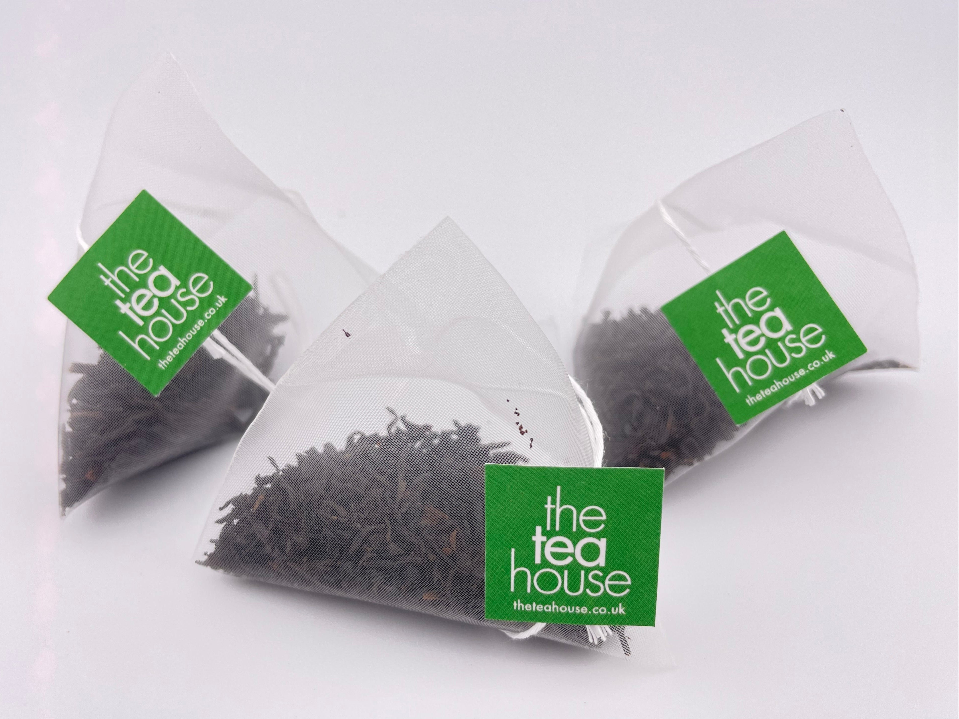Teabags containing loose leaf tea on white background