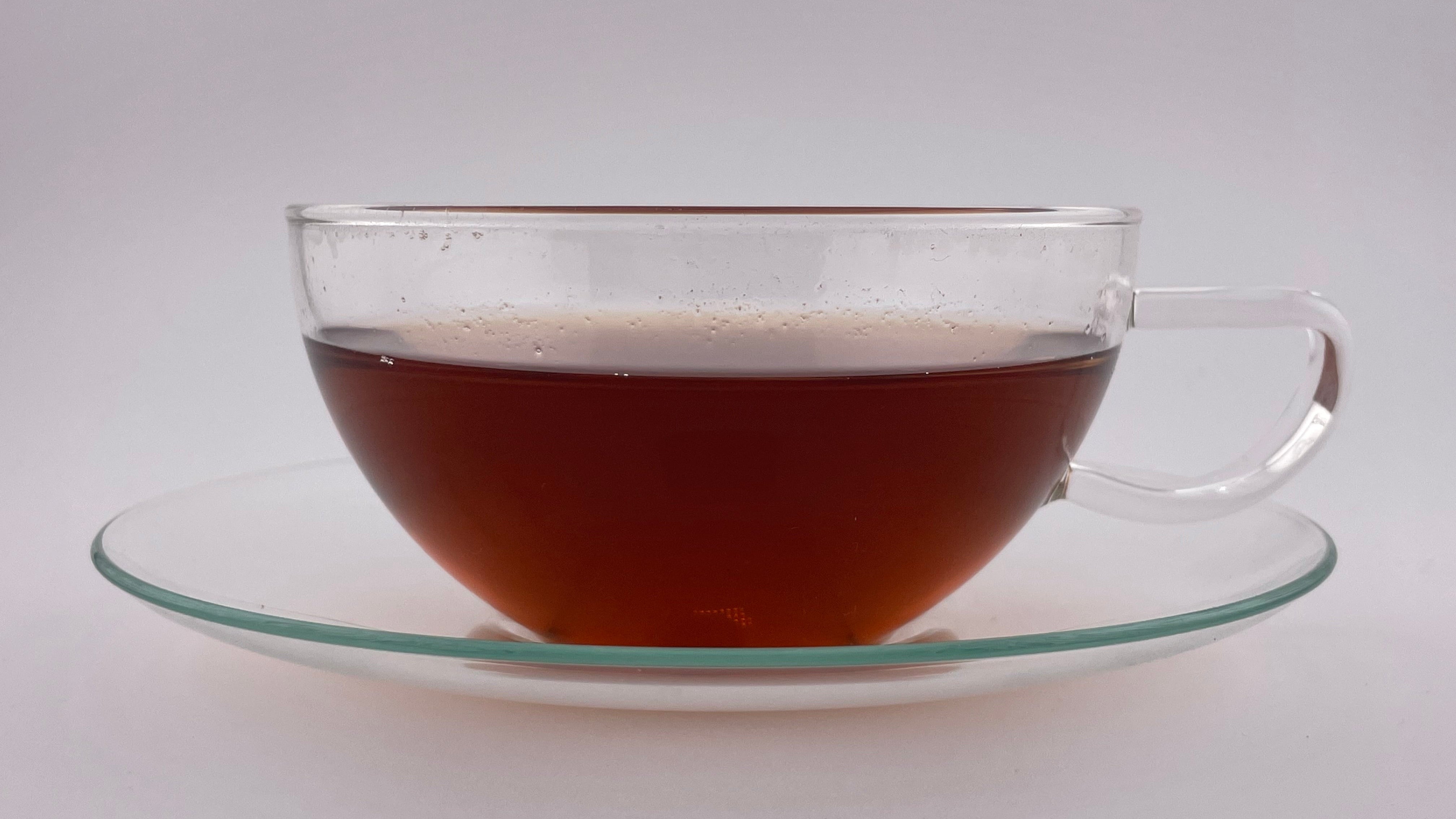 Clear glass teacup with tea on a white background