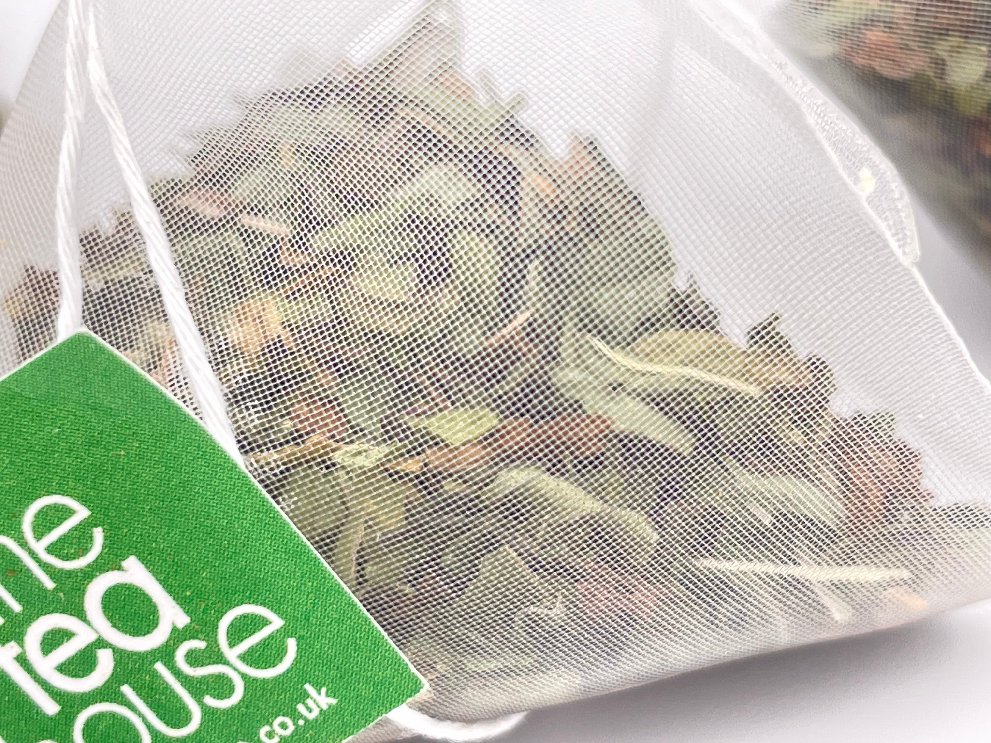 loose leaf peppermint in a teabag on white background with green tag "The Tea House"