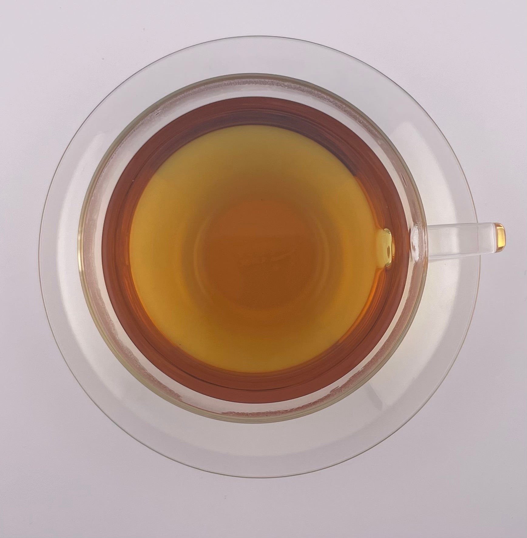 Clear tea cup with a yellowish liquid on a white background