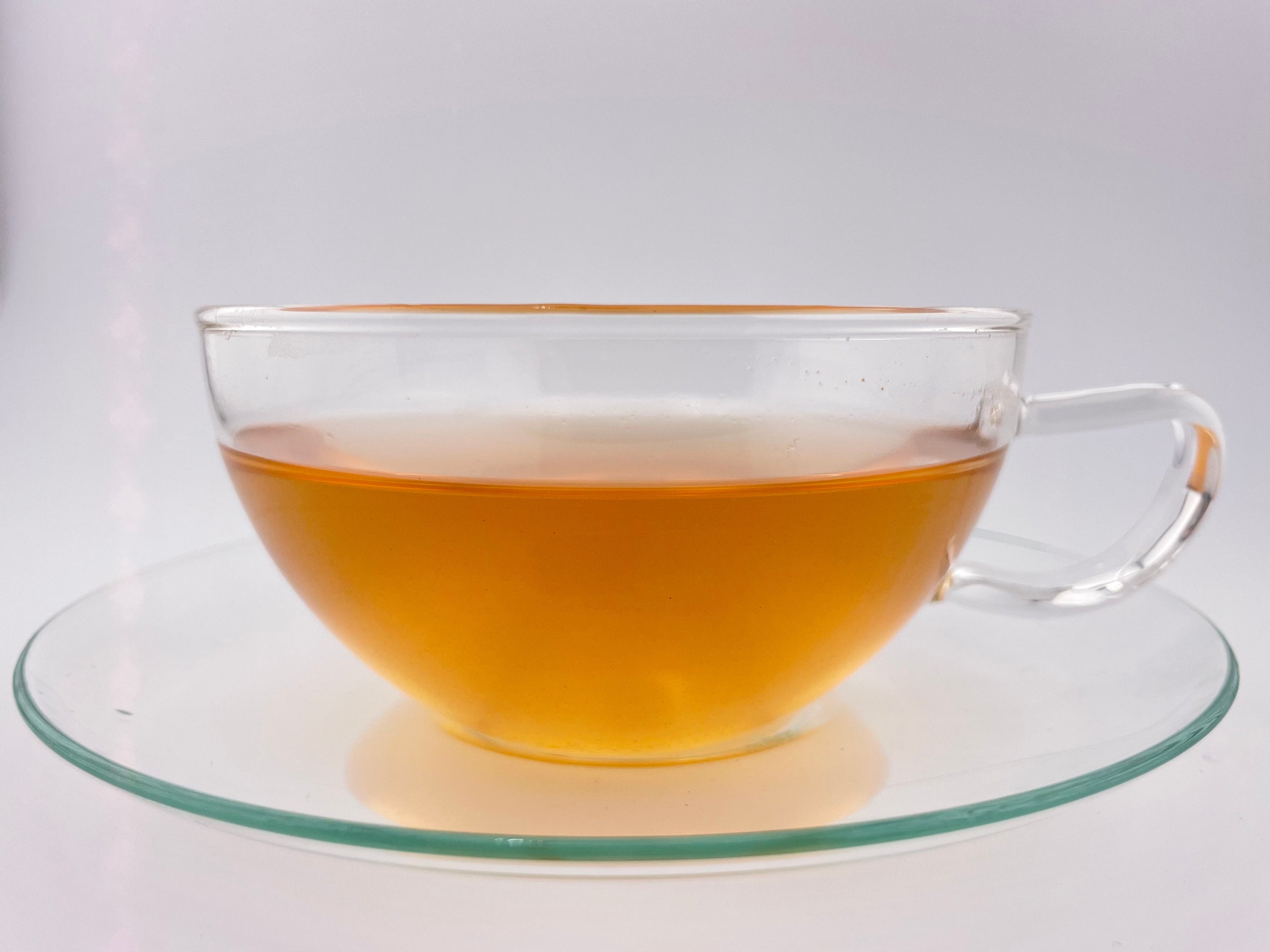 yellow orange liquor in clear teacup on white background