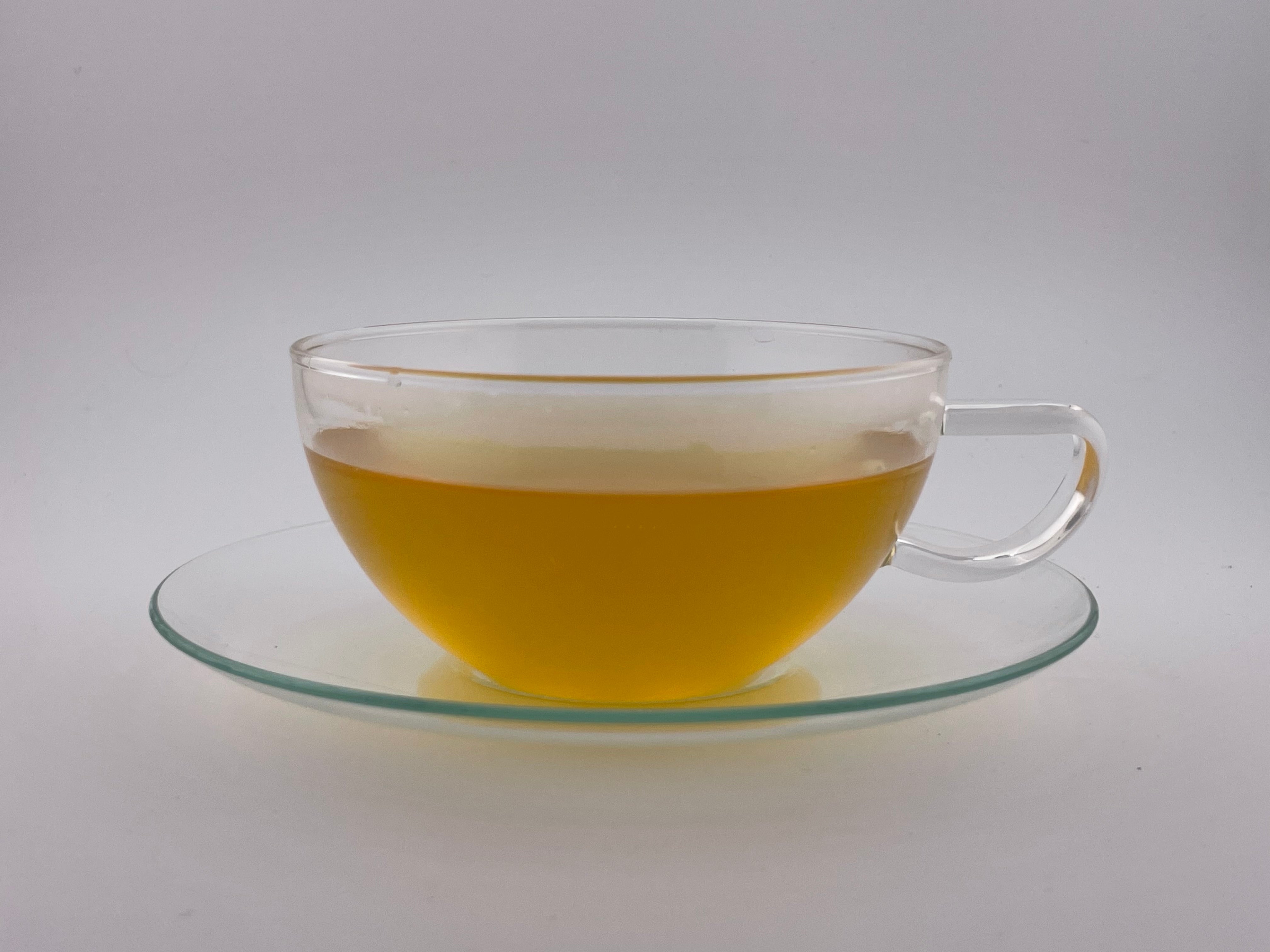 yellow liquor in a clear teacup on white background